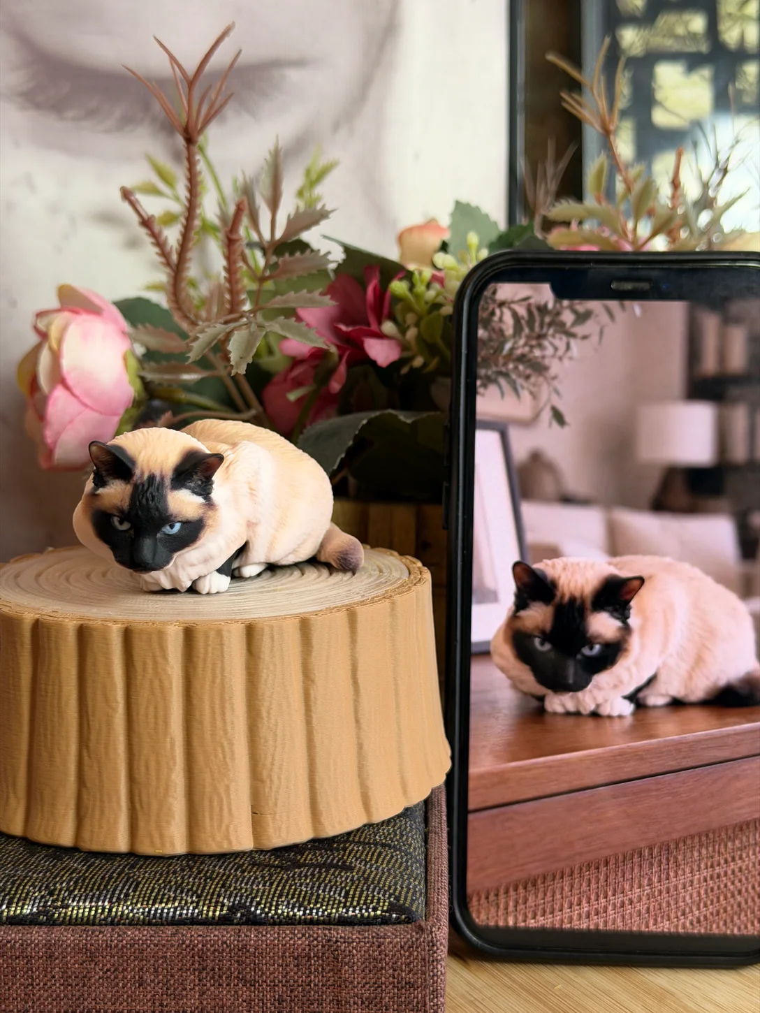 Point-colored cat figurine beside a phone displaying its reference photo