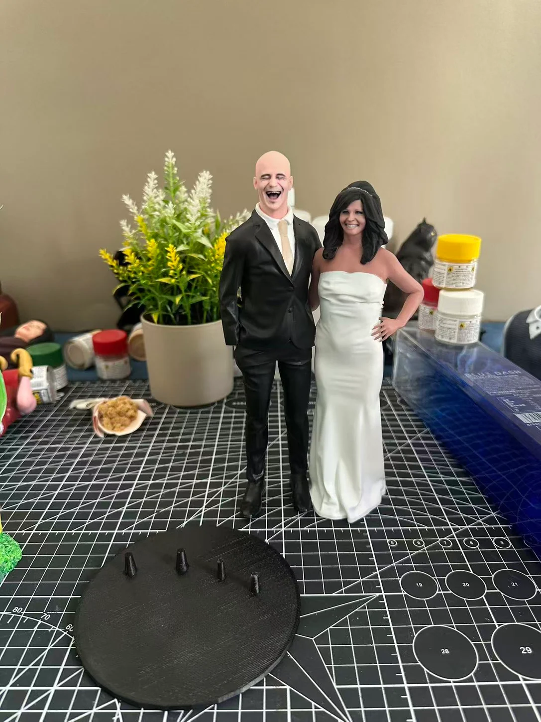 Bride and groom figurines in white dress and black suit on a studio workbench