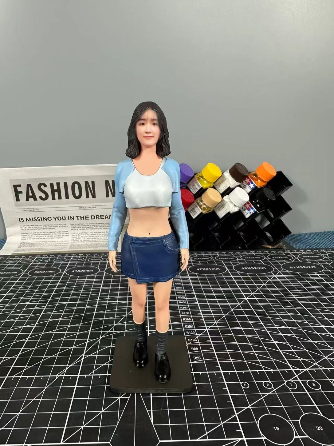 Finished portrait figurine in a blue cardigan, white top, blue skirt and black boots