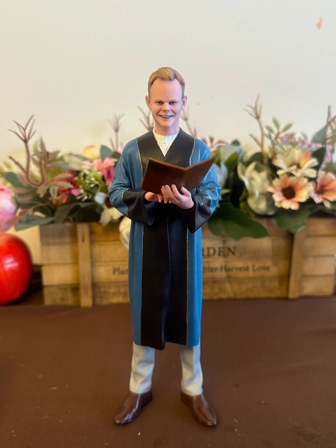 Finished portrait figurine in a blue and black robe holding an open book